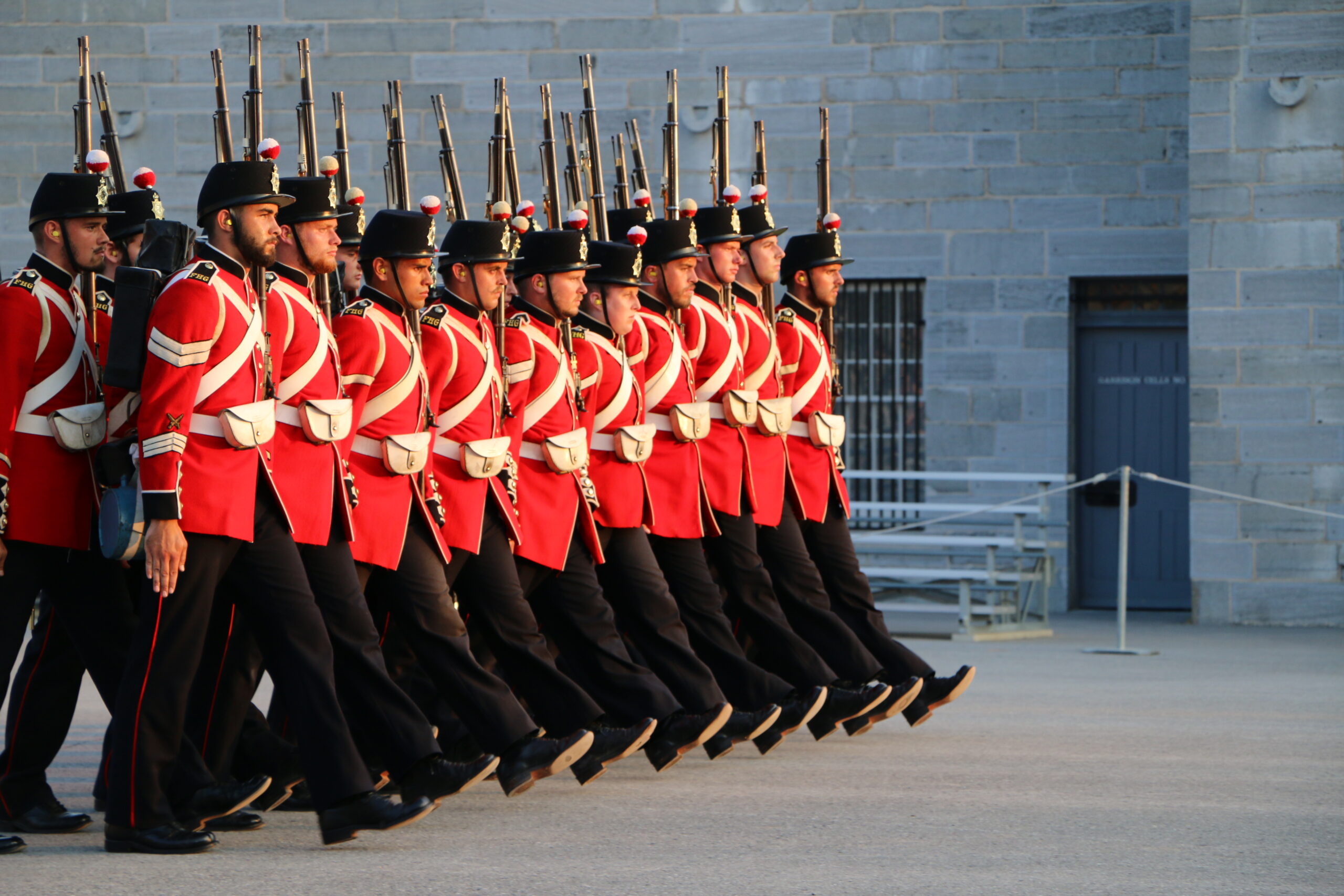 Fort Henry Guard in red military uniforms marching on the Parade Square.
